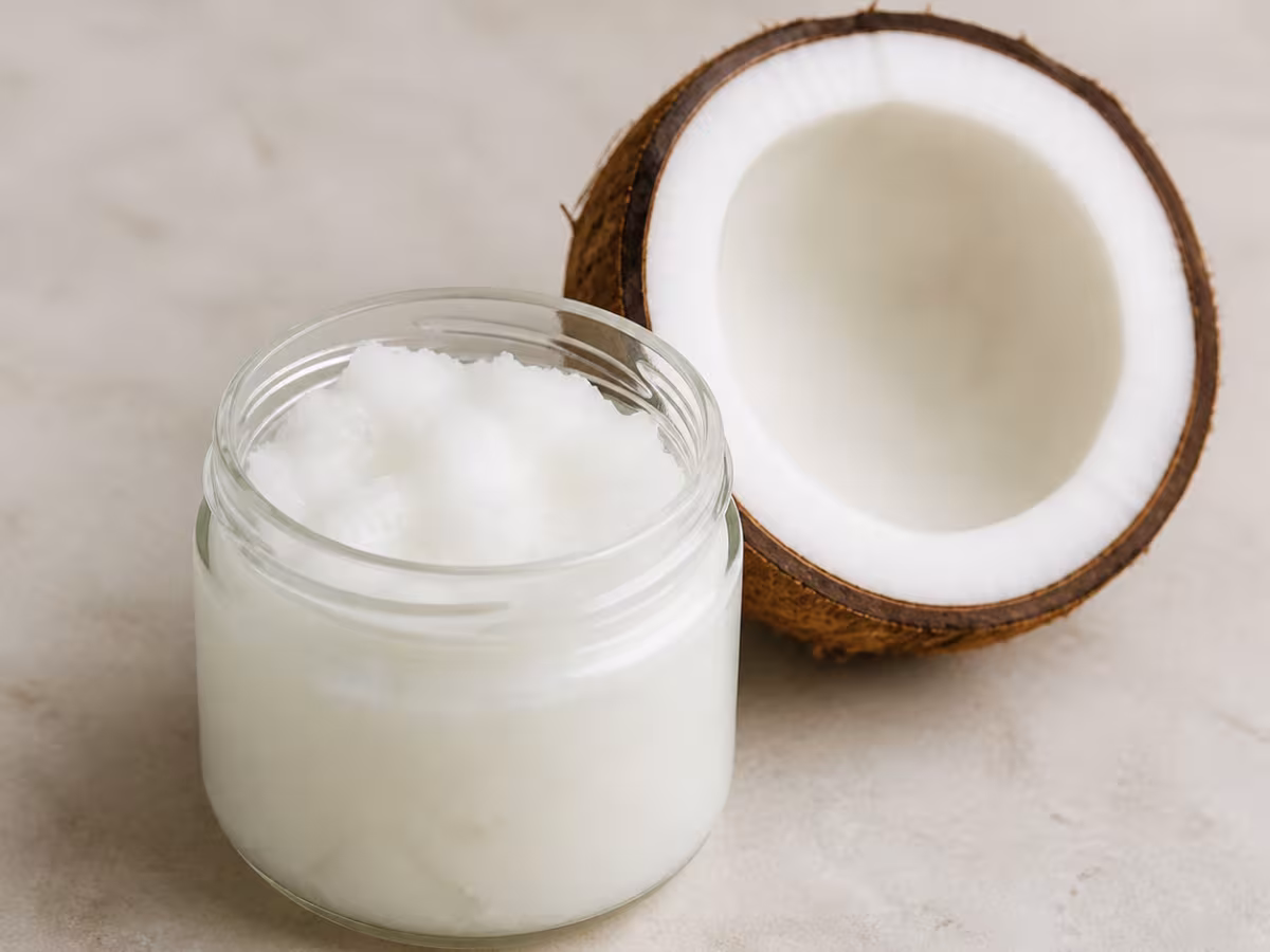 Aceite de coco s&oacute;lido en un cuenco junto a un coco abierto