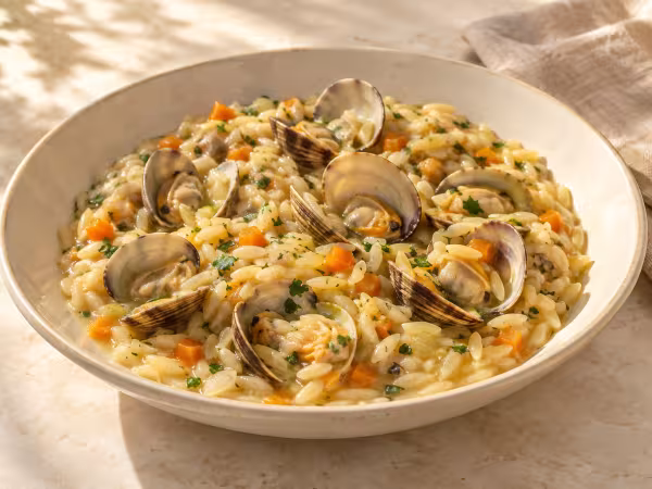 Orzo meloso con almejas al vino blanco servido