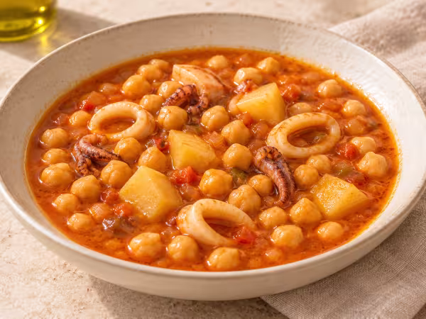 Brothy chickpea stew with squid rings and potato chunks in an ivory bowl
