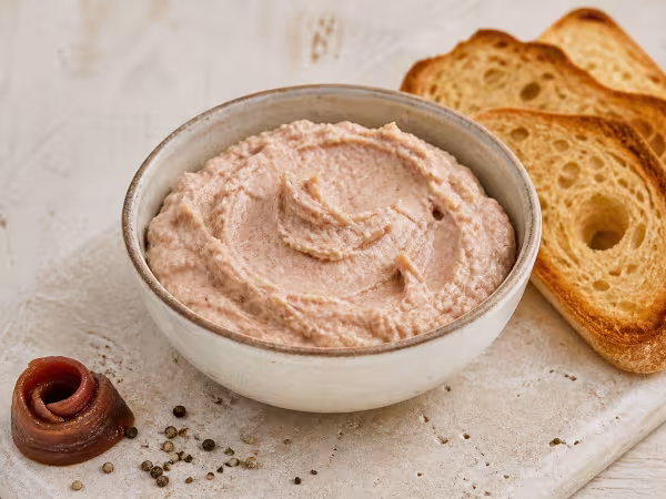 Pat&eacute; cremoso de anchoas y at&uacute;n en un cuenco de cer&aacute;mica acompa&ntilde;ado de tostadas