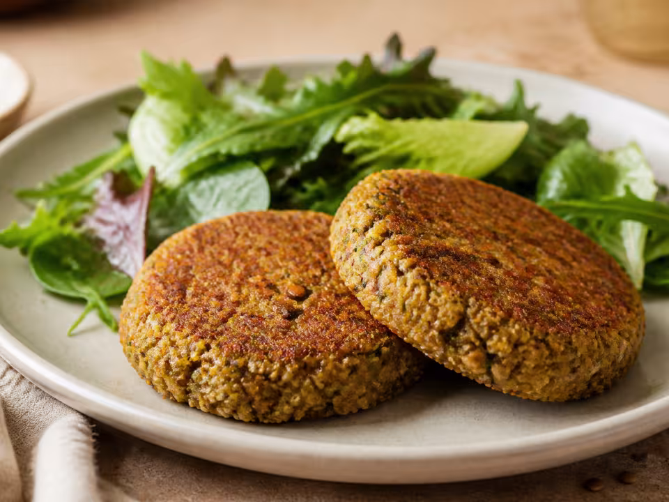 Hamburguesas vegetales doradas de lentejas y quinoa con ensalada verde