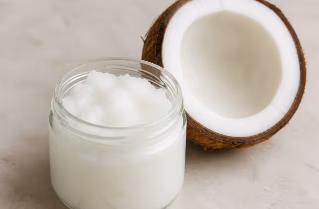 Aceite de coco sólido en un cuenco junto a un coco abierto