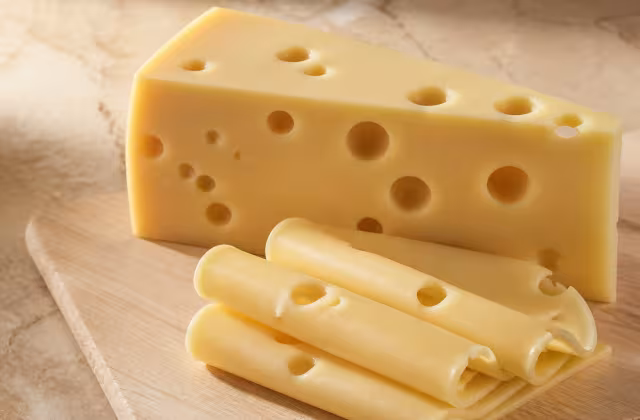 Cuña y lonchas de queso emmental de color amarillo pálido